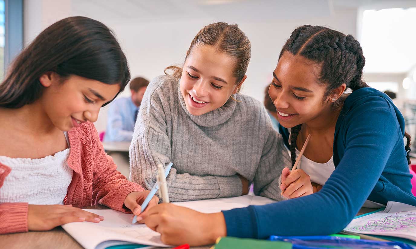 Three middle school girls working collaboratively on a math project.